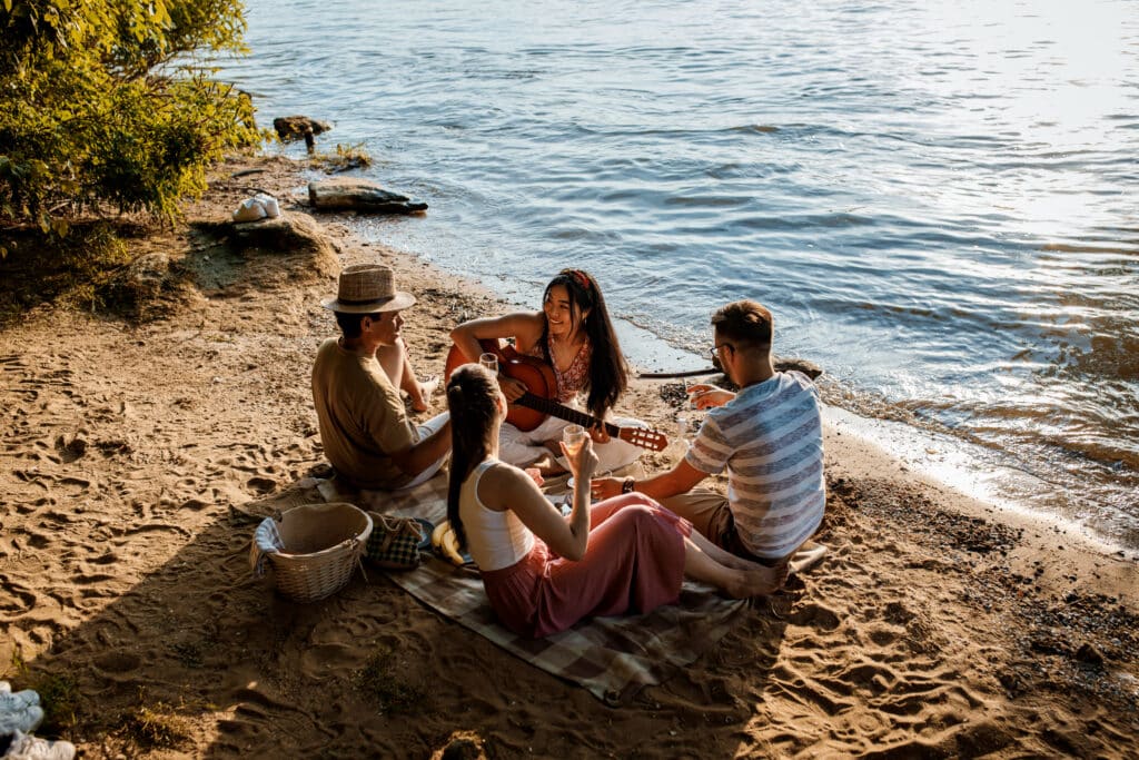 Friends enjoying a peaceful beach picnic with a guitar, relaxing far away from the crowds on a private Komodo charter.